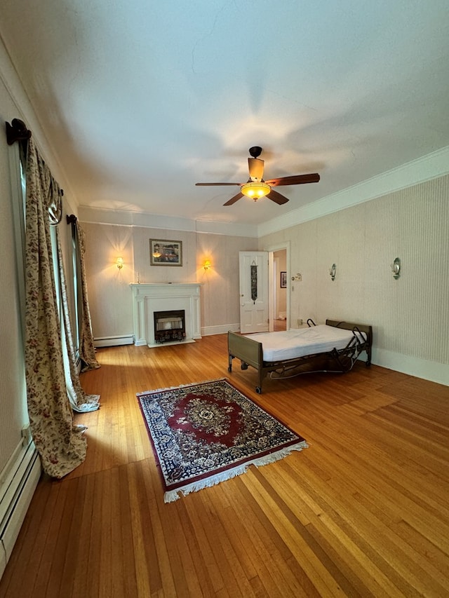 bedroom with baseboard heating, ceiling fan, crown molding, and hardwood / wood-style flooring