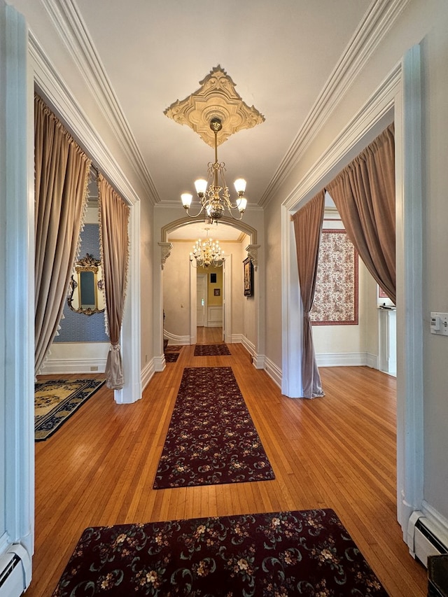 hall with a baseboard radiator, hardwood / wood-style flooring, and ornamental molding