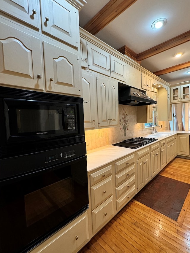 kitchen featuring backsplash, black appliances, sink, light hardwood / wood-style flooring, and beamed ceiling