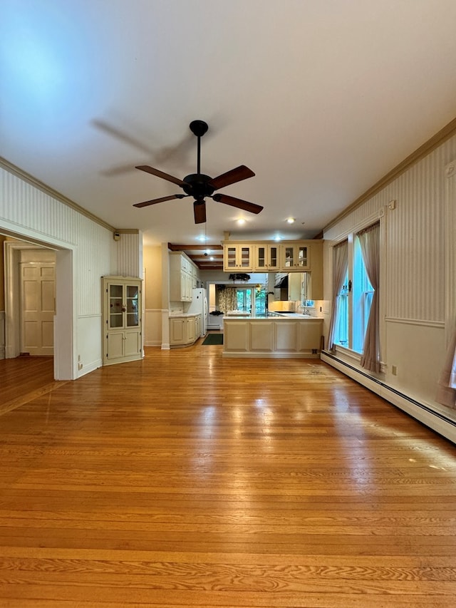 unfurnished living room with a baseboard heating unit, light hardwood / wood-style floors, ceiling fan, and ornamental molding