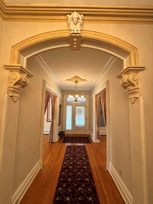 doorway to outside with crown molding, dark hardwood / wood-style flooring, a baseboard heating unit, and a notable chandelier