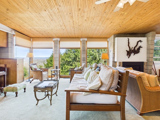 carpeted living area featuring ceiling fan, exterior fireplace, and wooden ceiling
