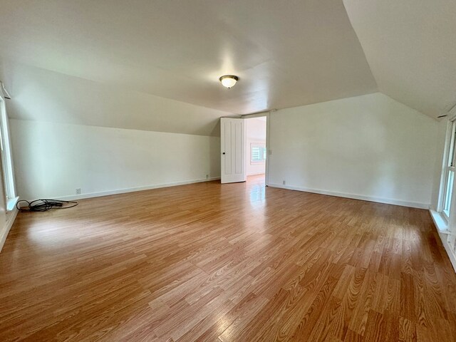 additional living space featuring vaulted ceiling and light wood-type flooring