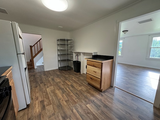 kitchen featuring dark wood-type flooring, white refrigerator, crown molding, and gas stove