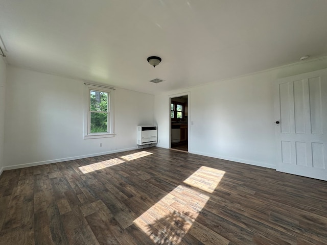 unfurnished living room with dark hardwood / wood-style floors and heating unit