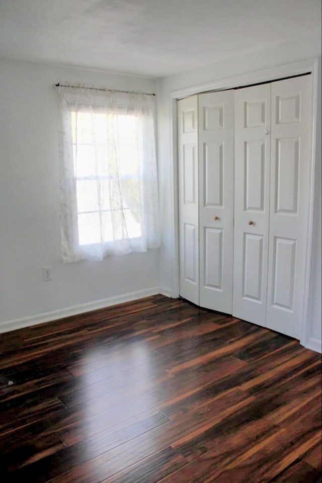 unfurnished bedroom featuring a closet and dark wood-type flooring