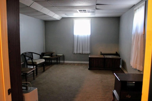 sitting room featuring plenty of natural light, carpet, and a drop ceiling