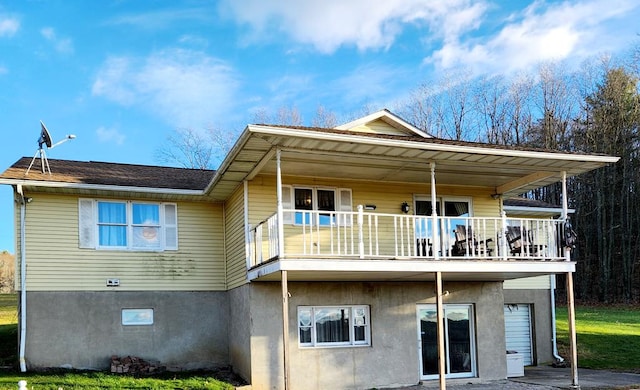 rear view of house featuring a balcony and a garage