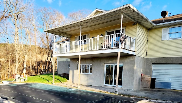 back of property with a garage and a balcony