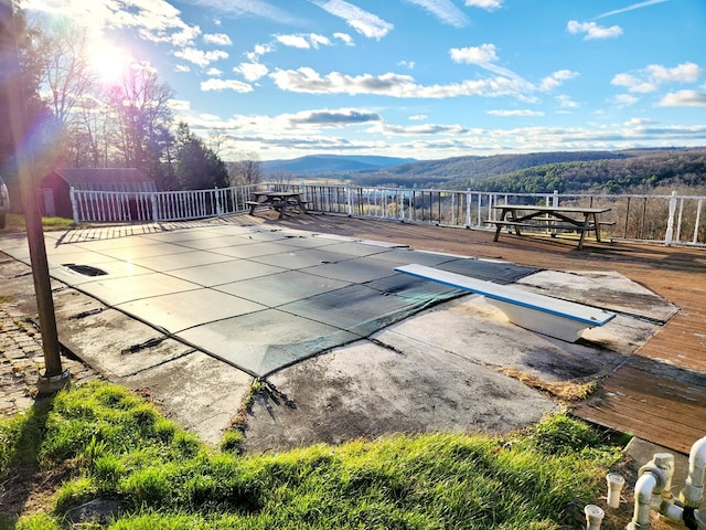 view of pool featuring a deck with mountain view and a diving board