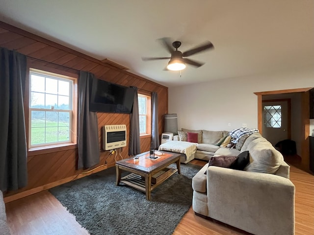 living room with ceiling fan, wood walls, a wealth of natural light, and heating unit