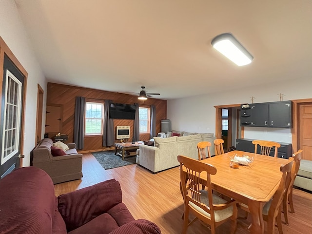 dining space featuring hardwood / wood-style floors, ceiling fan, and wood walls