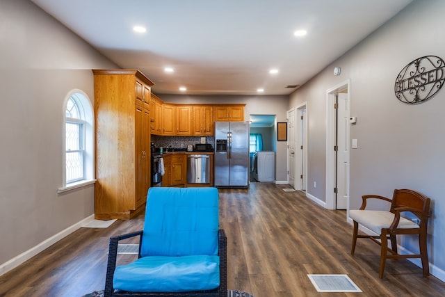 kitchen with backsplash, washer / clothes dryer, dark wood-type flooring, and appliances with stainless steel finishes