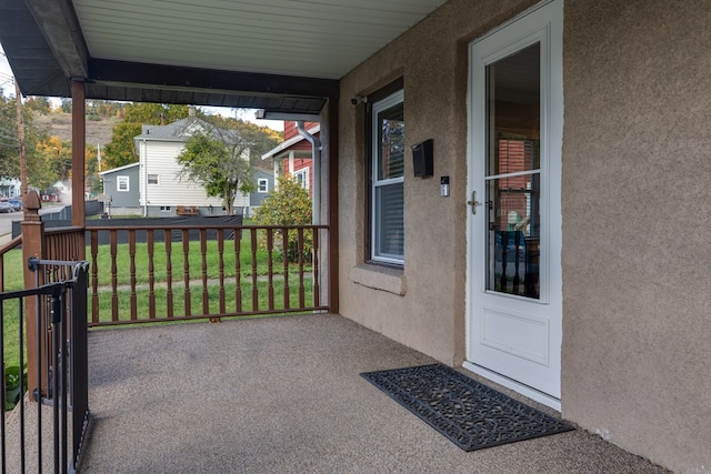 view of exterior entry with a lawn and a porch