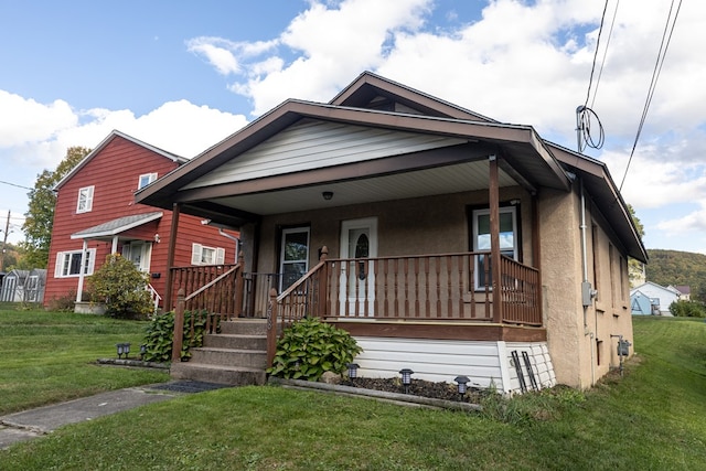 bungalow featuring covered porch and a front yard