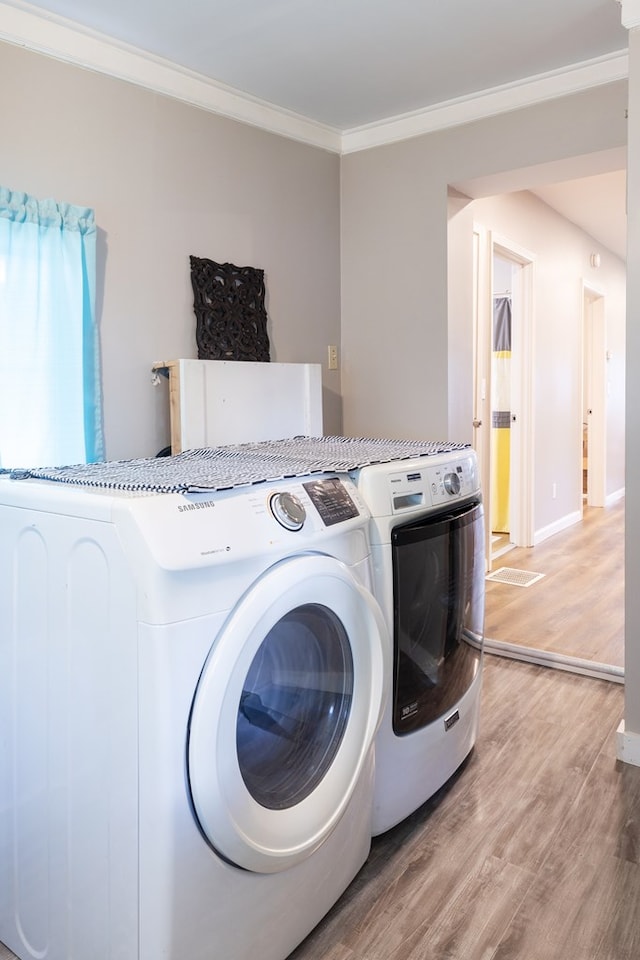 laundry area with hardwood / wood-style flooring, washer and clothes dryer, and ornamental molding