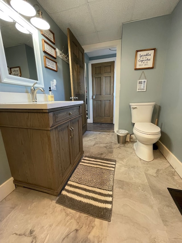 bathroom with a paneled ceiling, vanity, and toilet