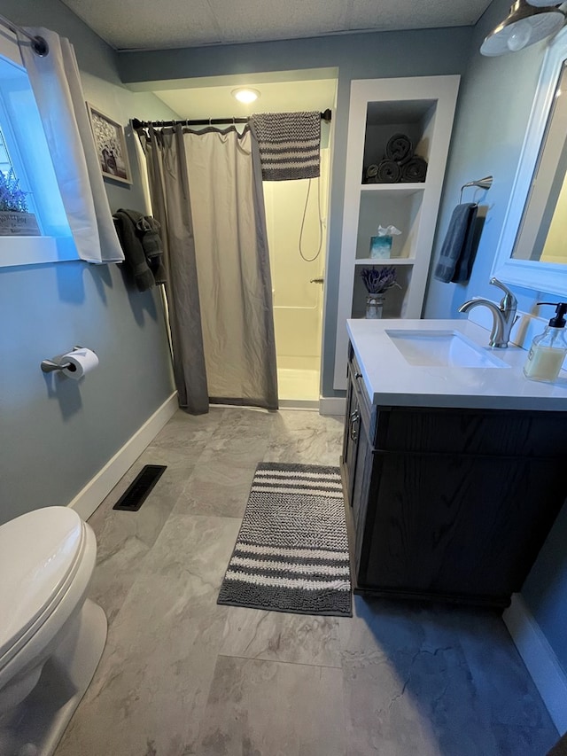 bathroom with toilet, built in features, vanity, and walk in shower