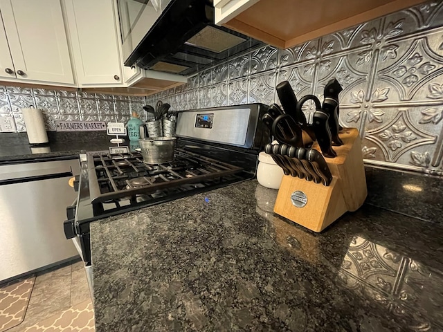 kitchen with decorative backsplash, white cabinetry, stainless steel appliances, and dark stone counters