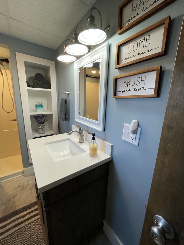 bathroom featuring a drop ceiling, a shower, built in features, and vanity