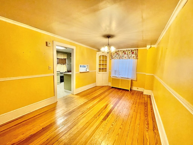 unfurnished dining area featuring radiator heating unit, an inviting chandelier, wood-type flooring, and ornamental molding