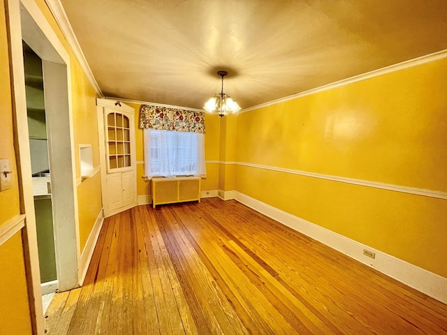 unfurnished room featuring radiator heating unit, wood-type flooring, a chandelier, and ornamental molding