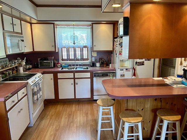 421 State St, Towanda, PA 18848 - kitchen featuring white appliances, light wood finished floors, crown molding, white cabinetry, and a breakfast bar area