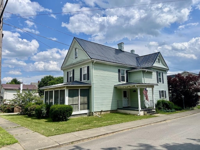 421 State St, Towanda, PA 18848 - view of front facade with a chimney, a sunroom, a metal roof, a standing seam roof, and a front yard