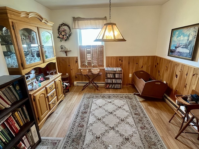 421 State St, Towanda, PA 18848 - living area featuring wainscoting, wood walls, light wood-style floors, and a baseboard radiator