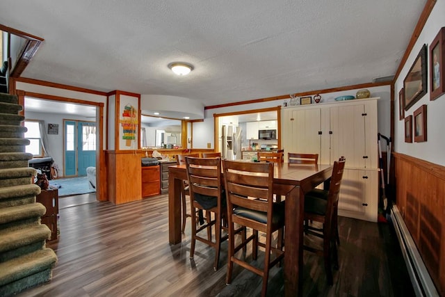 dining space with a textured ceiling, a baseboard heating unit, dark hardwood / wood-style floors, and ornamental molding