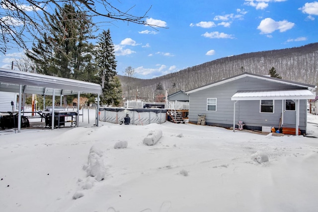 snow covered back of property featuring a mountain view