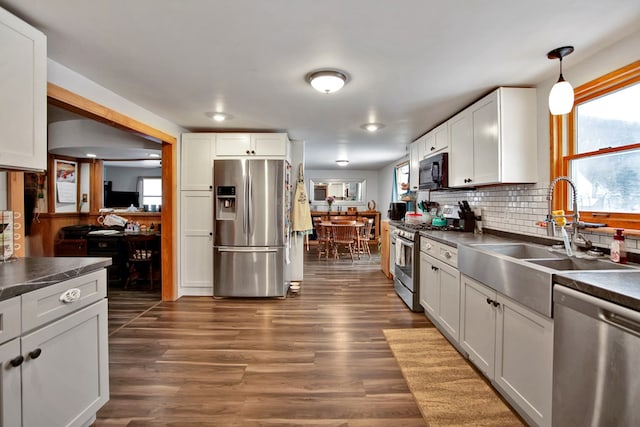 kitchen with appliances with stainless steel finishes, sink, pendant lighting, and white cabinetry