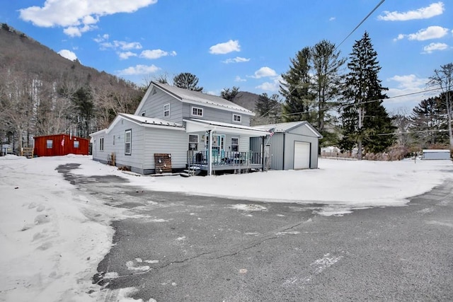 view of property with a garage, an outdoor structure, a mountain view, and a porch