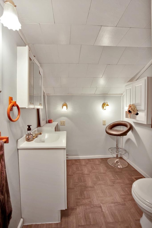 bathroom with toilet, vanity, and parquet floors