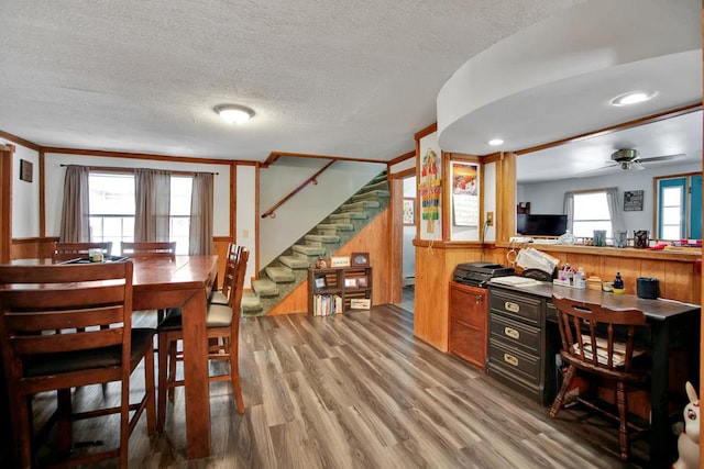 dining room featuring hardwood / wood-style flooring, ornamental molding, a textured ceiling, and ceiling fan