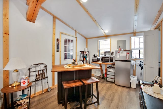 kitchen featuring light hardwood / wood-style floors, vaulted ceiling, appliances with stainless steel finishes, a kitchen bar, and wooden counters