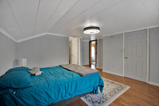 bedroom featuring crown molding, lofted ceiling, and wood-type flooring