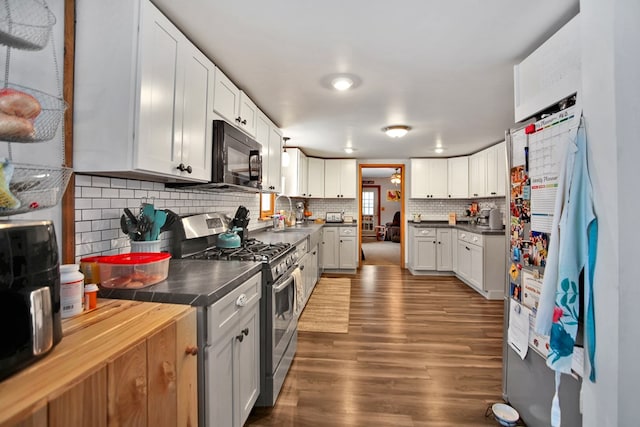 kitchen featuring sink, backsplash, white cabinetry, dark hardwood / wood-style flooring, and stainless steel range with gas cooktop