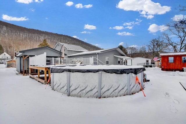 snow covered back of property featuring a pool side deck