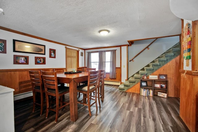 dining room with baseboard heating, ornamental molding, dark hardwood / wood-style flooring, and wood walls