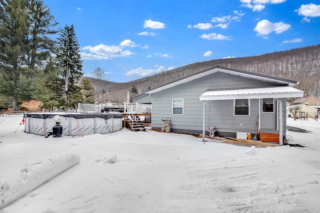 snow covered rear of property featuring a swimming pool side deck with mountain view