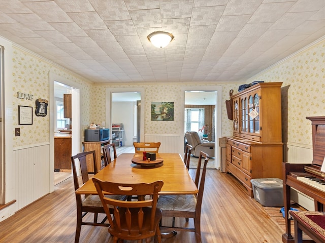 dining area with ornamental molding and light hardwood / wood-style flooring