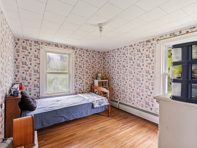 bedroom with hardwood / wood-style floors and baseboard heating