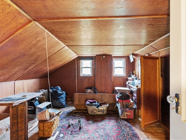 additional living space with wooden walls, hardwood / wood-style floors, wooden ceiling, and vaulted ceiling