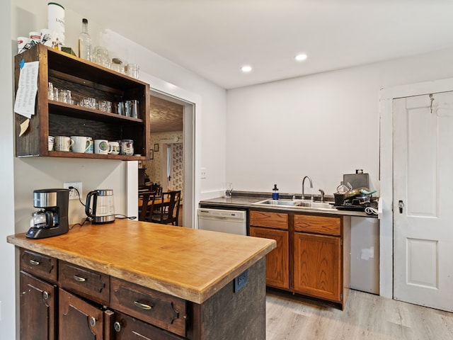 kitchen featuring butcher block counters, dishwashing machine, sink, and light wood-type flooring