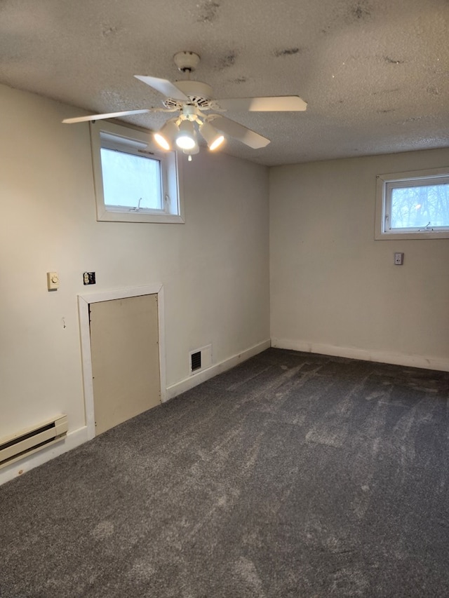 spare room with visible vents, a baseboard radiator, ceiling fan, a textured ceiling, and dark carpet