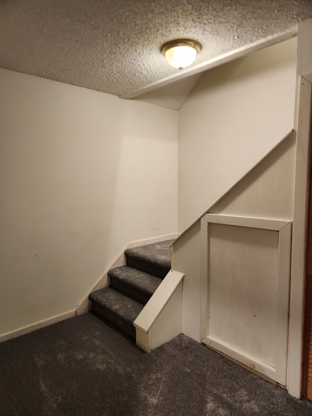 stairs with a textured ceiling, carpet floors, and vaulted ceiling