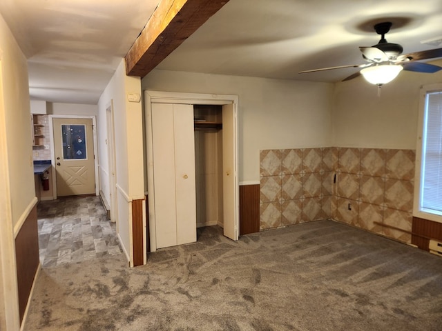 unfurnished bedroom with carpet floors, a closet, wainscoting, and ceiling fan