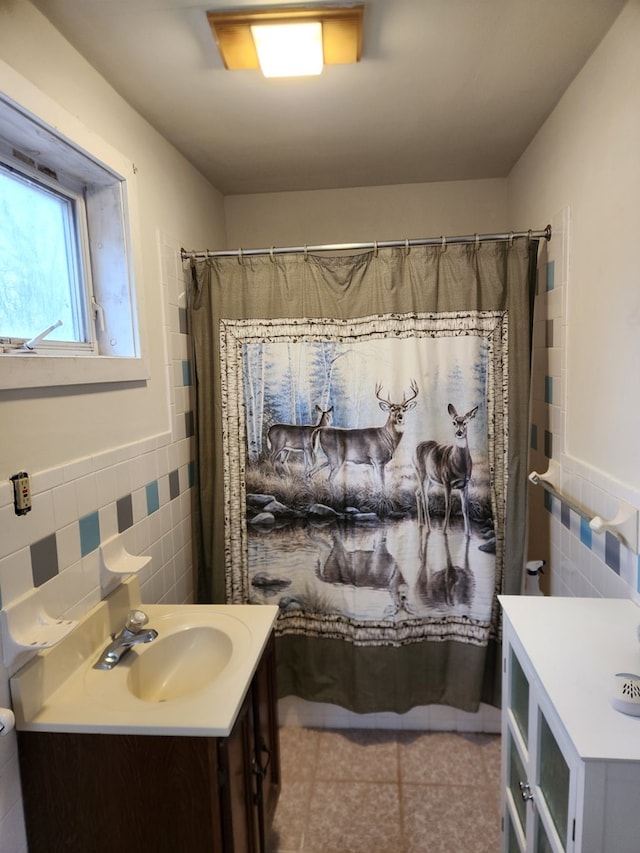 bathroom with a wainscoted wall, tile patterned floors, vanity, and tile walls