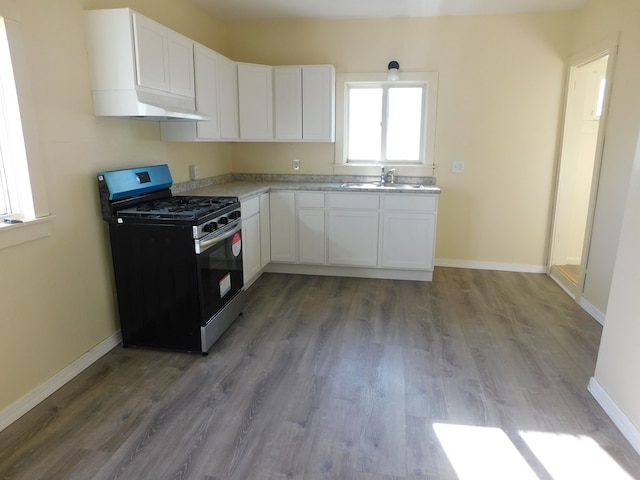 kitchen featuring stainless steel gas range oven, white cabinetry, and baseboards